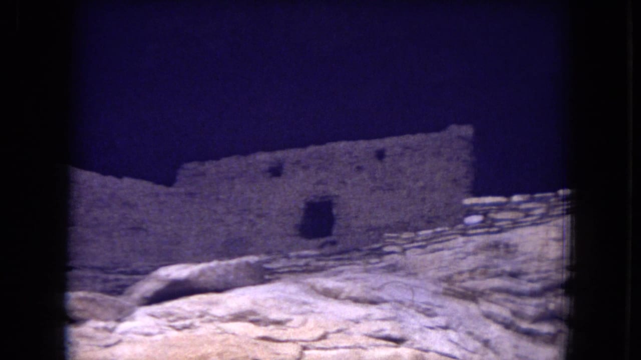 Weathered stone ruins above pale rock under a dark blue sky.