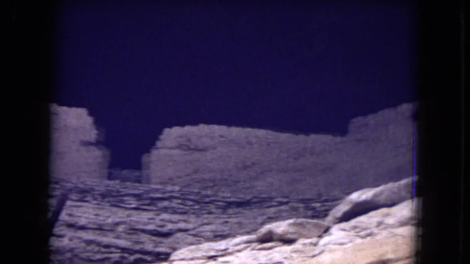 Handheld 8mm view of ancient-looking stone walls and rocky foreground in the Gila National Forest clip, with dark gate edges visible.