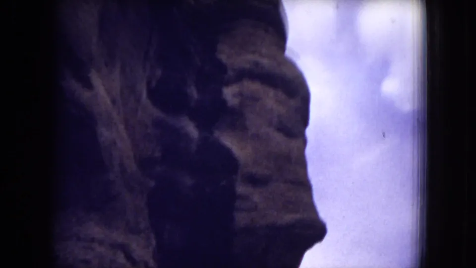 The final 8mm frame shows a vertical sandstone formation and shadowed rock face against a cloudy New Mexico sky.