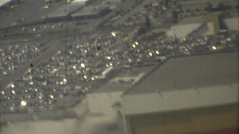 1973 Mexico City aerial footage looking down toward a busy airport parking lot and adjacent paved airport area.