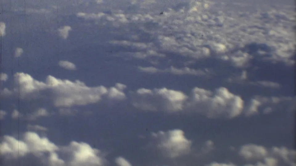 Final 8mm frame shows a soft blue sky and cloud layer, continuing the passenger-window flight view from Mexico City.
