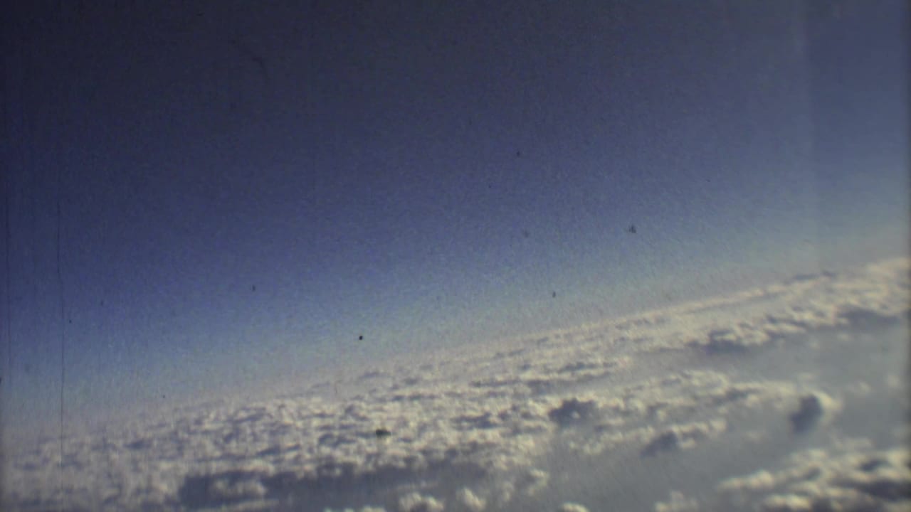 Blue sky above a broad layer of white clouds seen from an airplane.