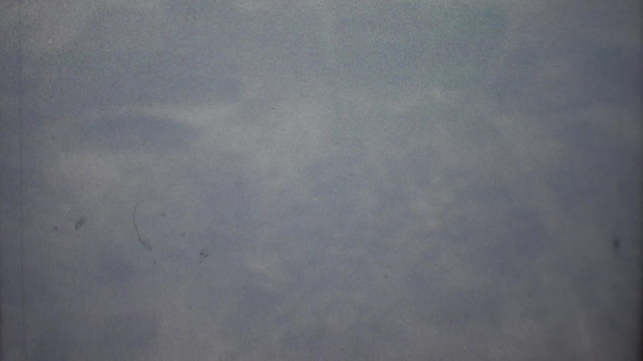 Soft gray-blue haze with faint cloud or landscape texture and visible film dust.