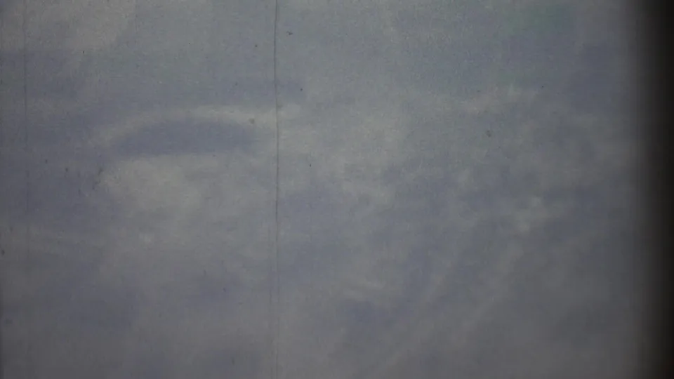 Hazy 1973 8mm travel frame with a vertical film line, soft focus, and faint overhead landscape or cloud shapes.