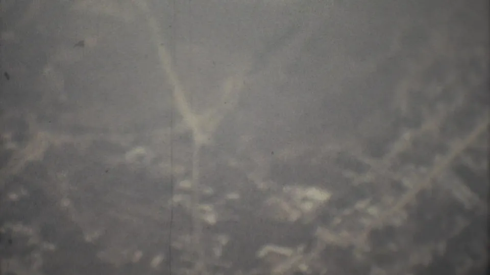 Hazy 1973 8mm frame suggesting a distant overhead landscape, with scratches, grain, and vertical film artifacts.