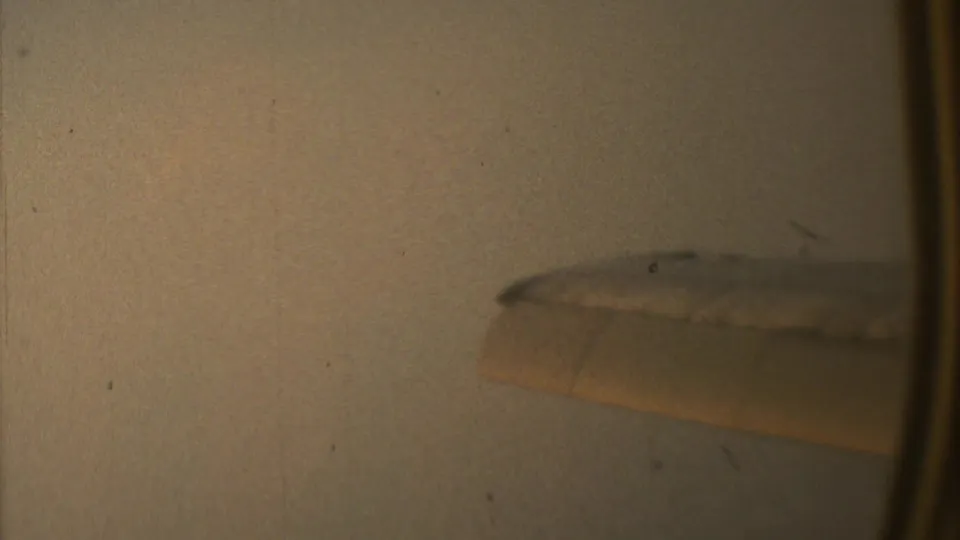 A small jet wing edge appears through a soft 1973 8mm frame over Mexico City, with little ground detail visible.