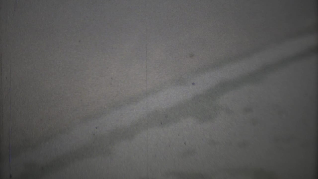 1973 Mexico City home-movie frame showing gray smoggy sky, faint shadow bands, grain, dust, and vertical film marks.