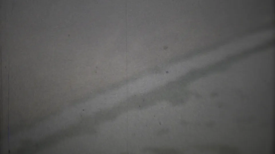 1973 Mexico City home-movie frame showing gray smoggy sky, faint shadow bands, grain, dust, and vertical film marks.