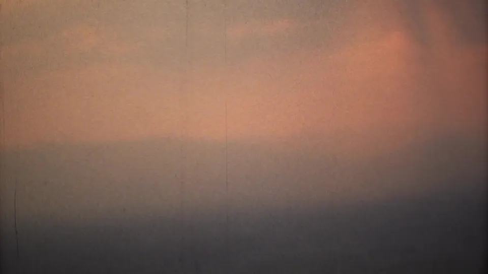 1973 Mexico City frame with orange smog glow fading into gray haze, dark banding, grain, and faint vertical scratches.