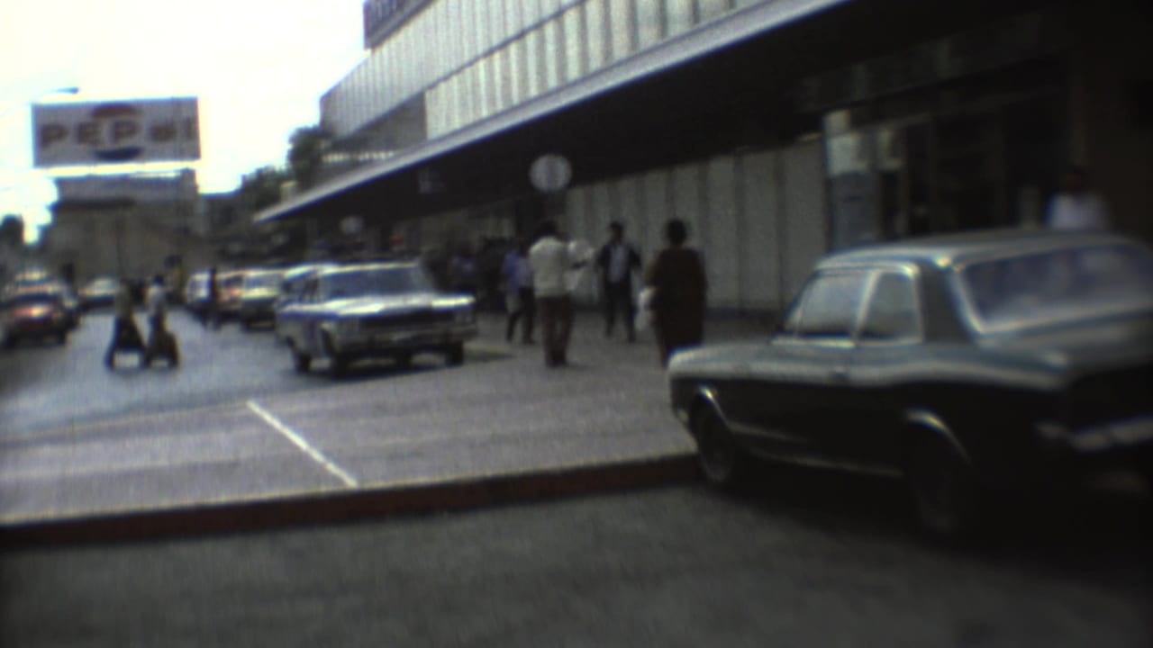 1973 Mexico City street view with pedestrians, period cars, commercial frontage, and a large Pepsi sign above the roadway.