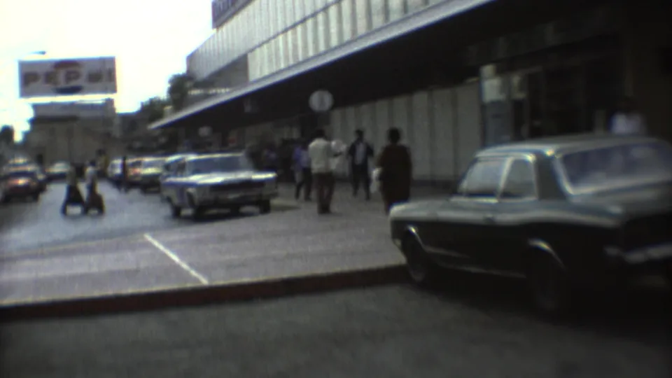 1973 Mexico City street view with pedestrians, period cars, commercial frontage, and a large Pepsi sign above the roadway.