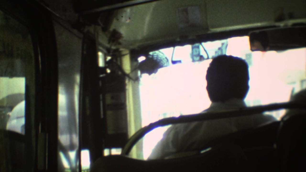 Interior bus view from 1973 Mexico City footage, showing a silhouetted passenger seated against a bright street-facing window.