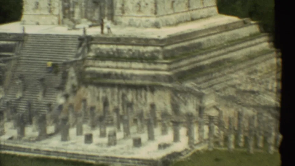 1973 Mexico City home-movie view of visitors climbing steep stone steps at ancient ruins, with tiered masonry in soft 8mm focus.