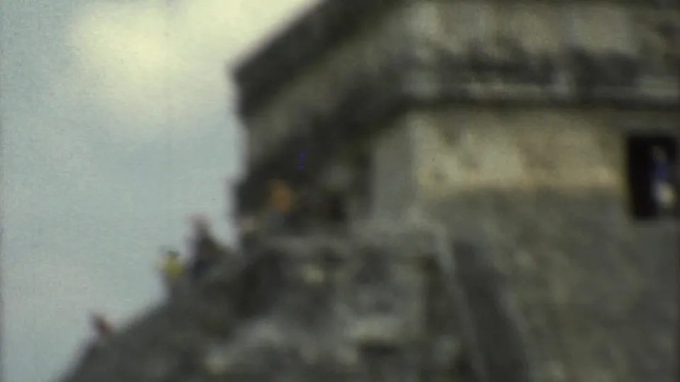 Blurred 1973 travel-film frame showing the upper section of El Castillo with visitors on the steps at Chichen Itza.