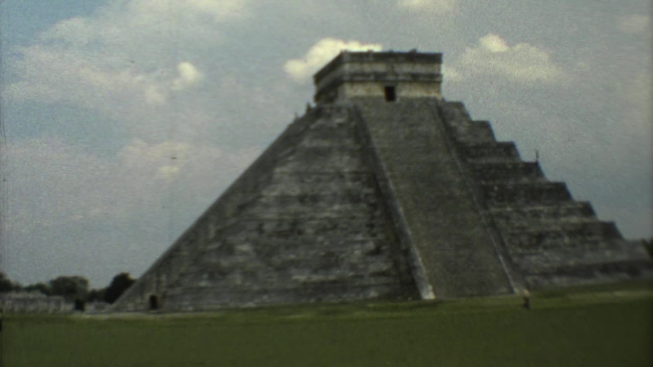 1973 8mm travel frame showing a large stepped pyramid at the Mexican archaeological site named in the metadata, seen across grass.