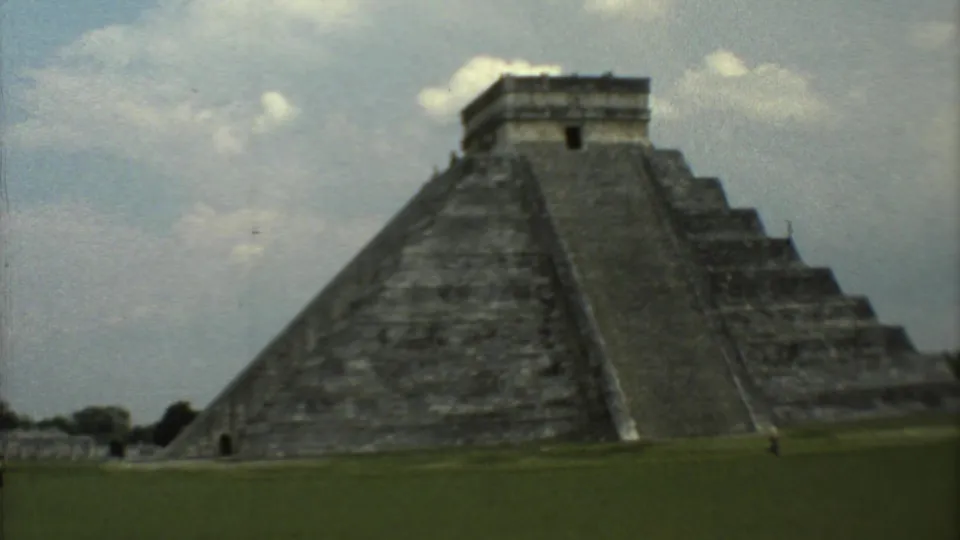 1973 8mm travel frame showing a large stepped pyramid at the Mexican archaeological site named in the metadata, seen across grass.