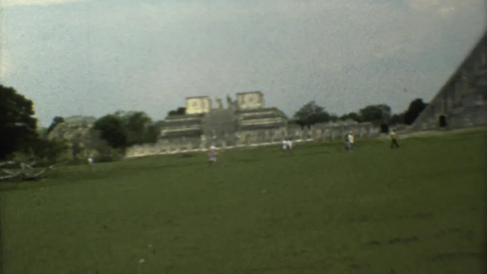 1973 8mm view of a grassy field before monumental stone ruins in Mexico City, with visitors scattered across the lawn.