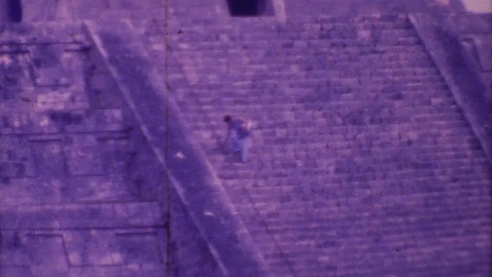 Purple-shifted 8mm frame of a lone visitor on the steep steps of a large stone pyramid in Mexico City.