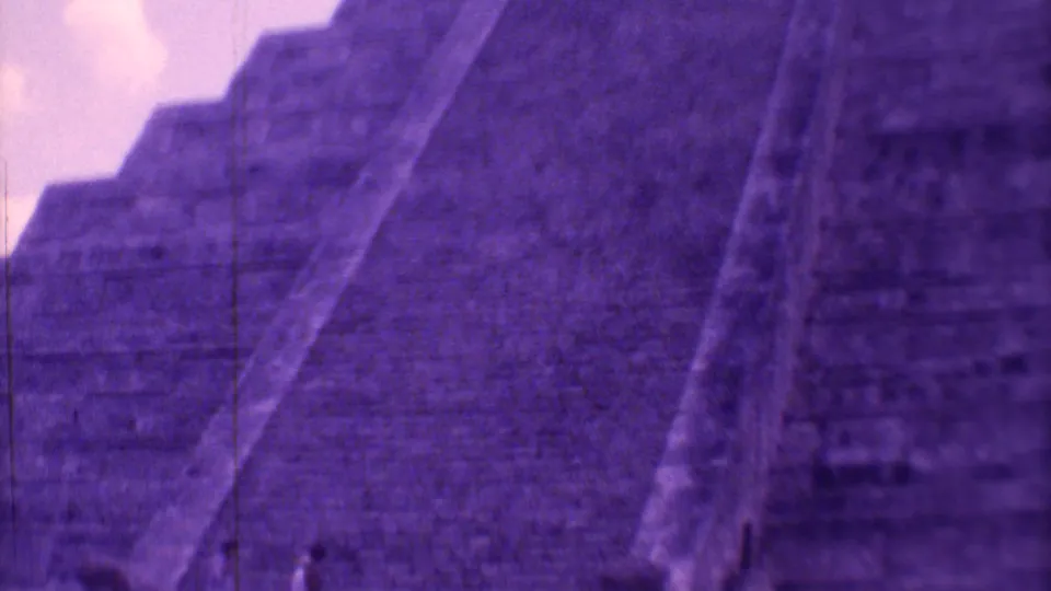 A close home-movie view emphasizes the scale of the stepped temple, with small tourists visible near the base in Mexico City.