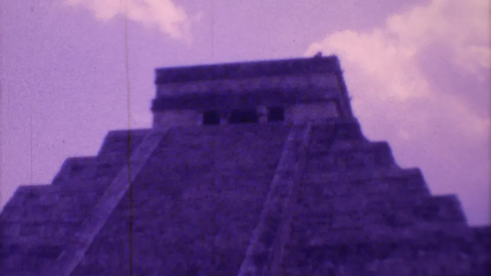 End frame holds on the upper portion of El Castillo, with the stairway cutting upward through purple-tinted grain and visible film scratches.
