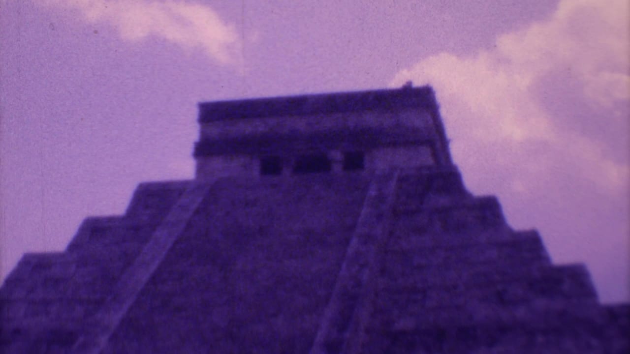 Low-angle view of a stepped stone pyramid beneath a purple-tinted sky.