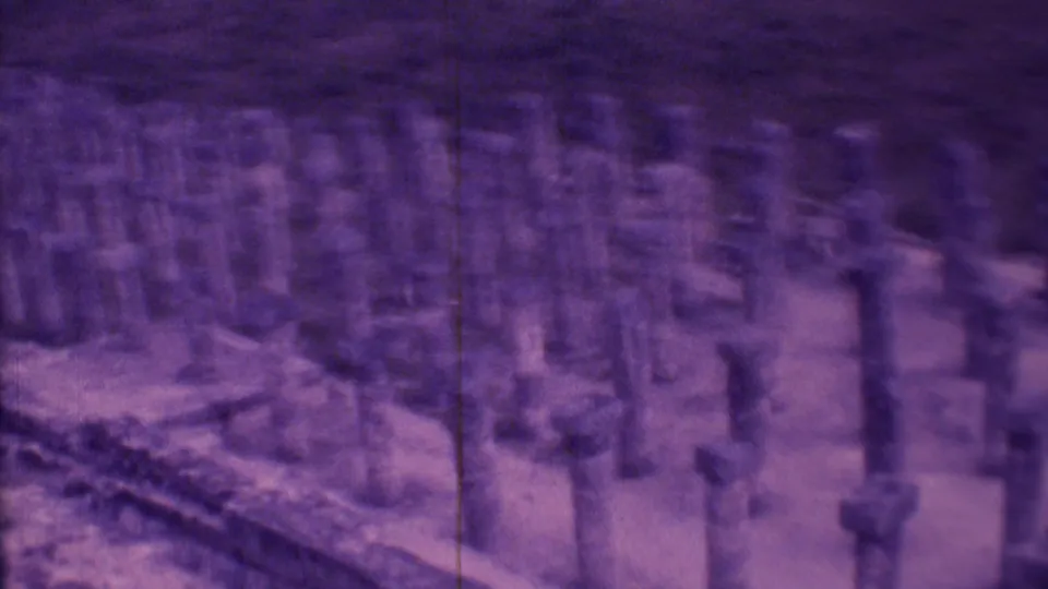 1973 Mexico City frame with clustered short pillars, low stone boundaries, and soft purple-tinted home-movie texture.