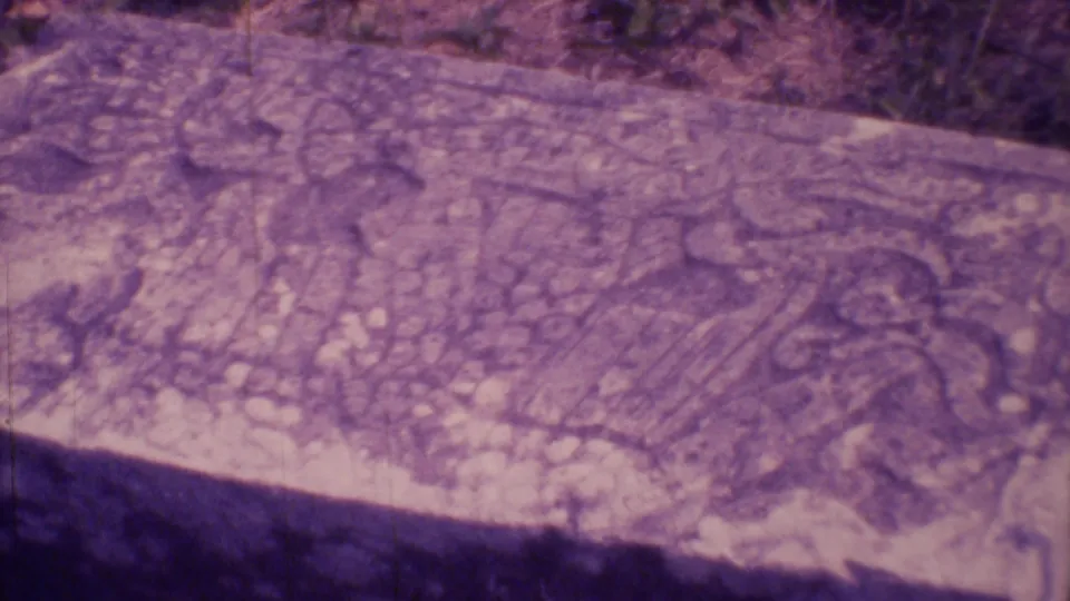 Close-up of a broad weathered carved stone surface in Mexico City, filmed from a handheld 8mm tour perspective.