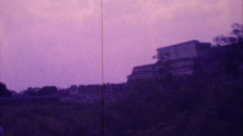 The final frame shows a distant hillside building and tree silhouettes under the purple cast of the 8mm scan.