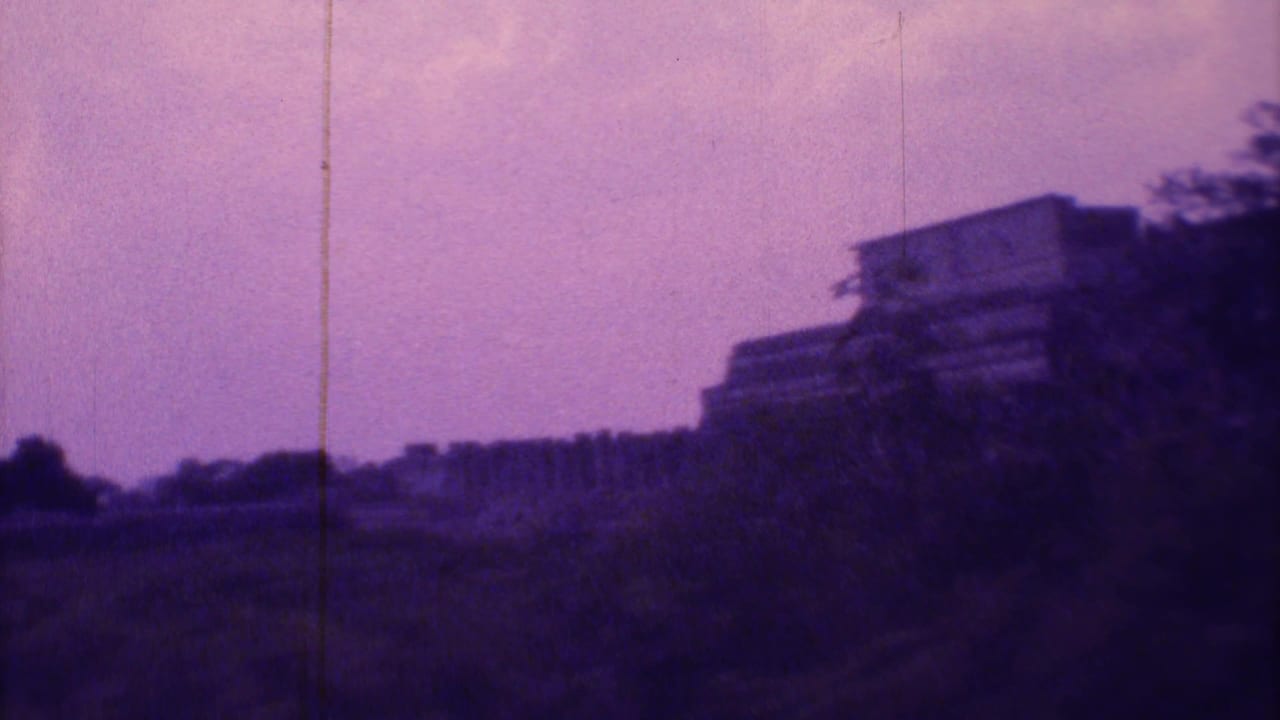 Distant stepped monument and low buildings seen across open terrain under a purple-tinted sky.