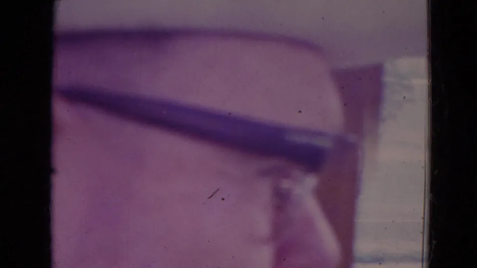 Soft 8mm frame from the 1974 Orlando flight, with a blurred aircraft structure crossing near dark window or film borders.