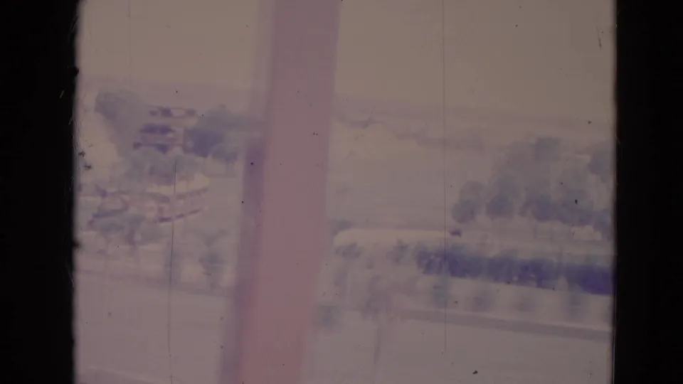1974 Orlando home-movie frame showing a hazy shoreline with trees, roadway-like bands, and visible 8mm frame borders.