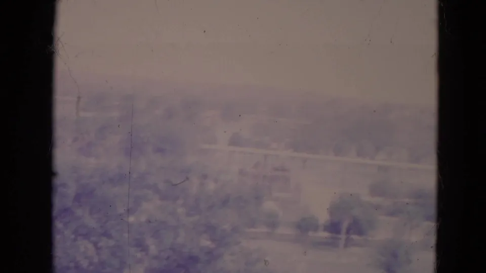 1974 Orlando home-movie view of a blurred riverside landscape, with trees, water, and aged-film dust and grain visible.
