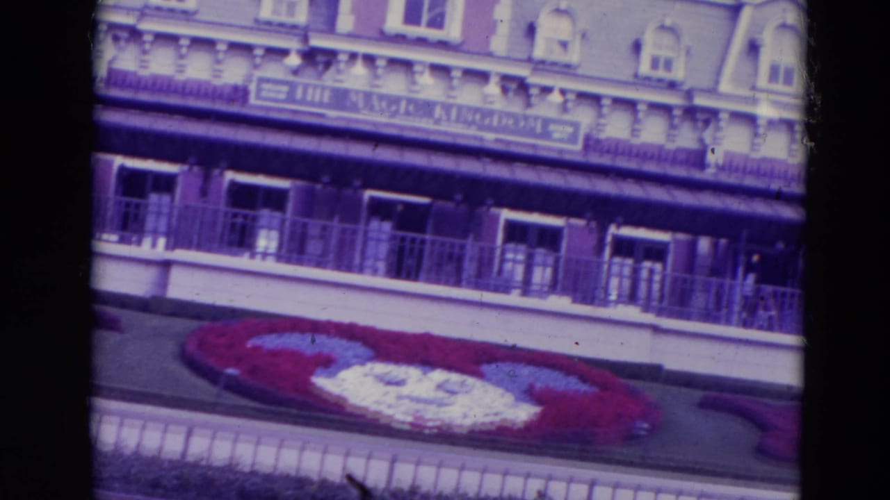 Walt Disney World entrance facade above a Mickey Mouse flower bed.