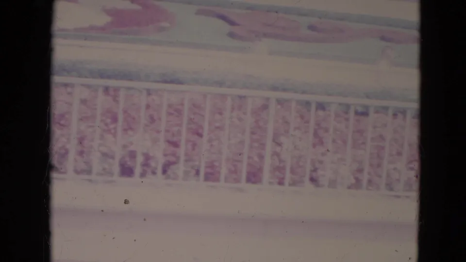 Faded 8mm frame from the 1974 Orlando clip showing a white railing and partially washed-out red floral planting.