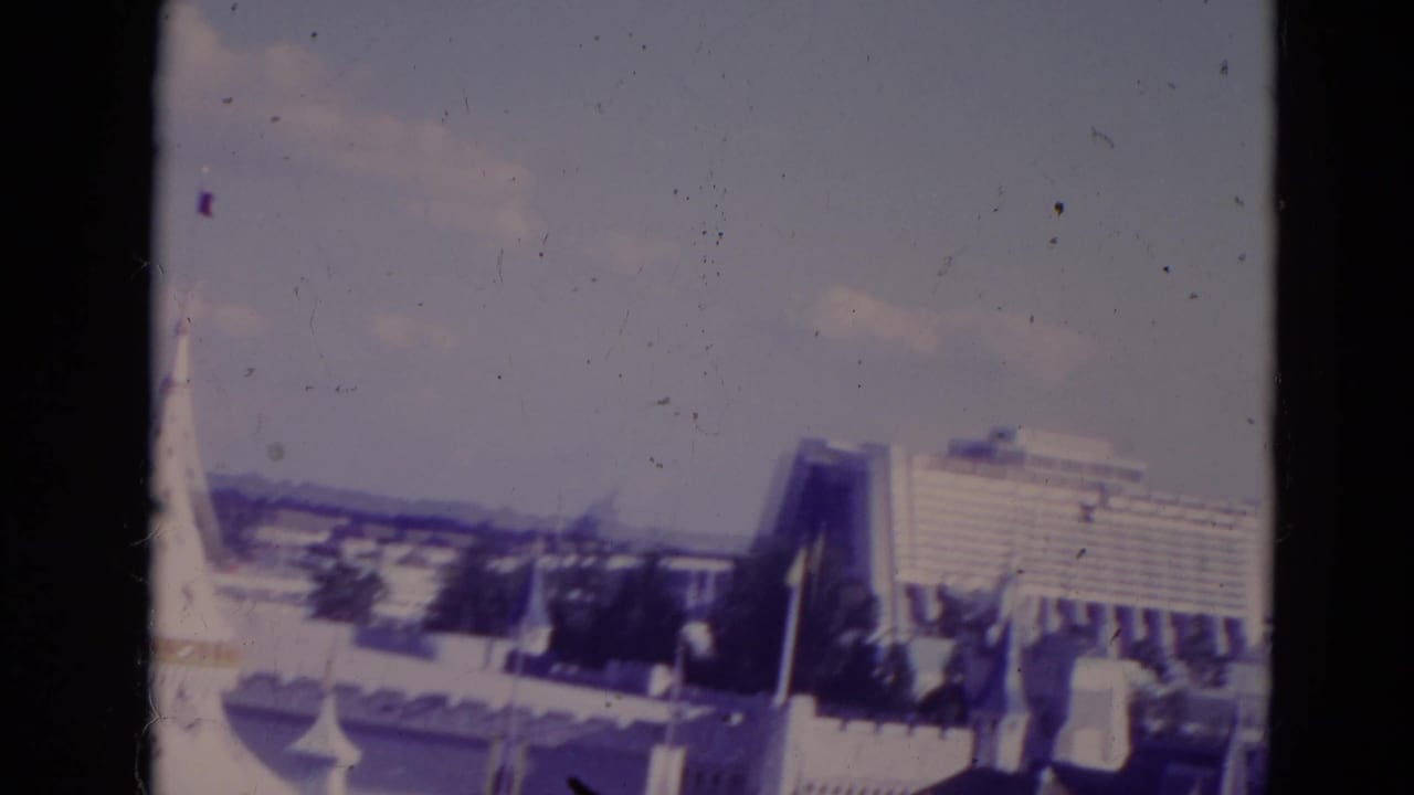 1974 Orlando 8mm frame showing the Contemporary Resort area and nearby theme-park structures under a pale sky.