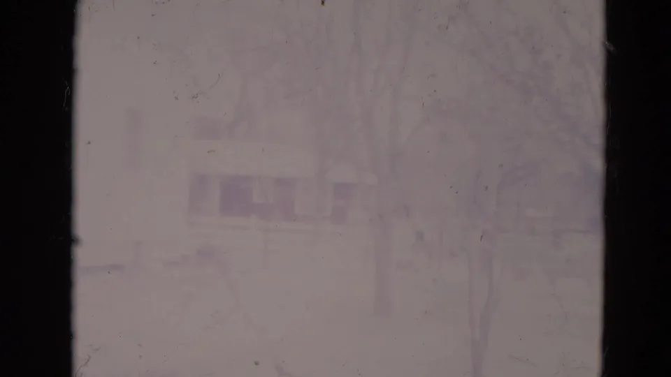 Faded 1974 Orlando frame with overexposed park building outlines and leafless branches barely visible.