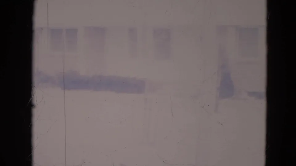 Faded 1974 Orlando 8mm frame showing a quiet suburban house exterior with windows, bare tree trunks, shrubs, and a small evergreen.