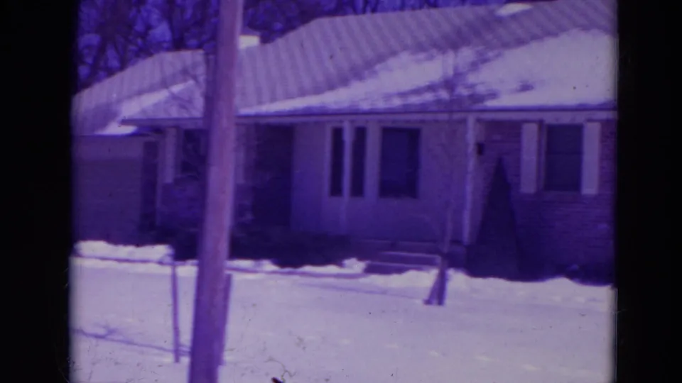 1974 Orlando home-movie view of a snow-covered ranch house, with a utility pole crossing the foreground and snow piled in the yard.