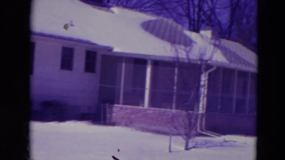 A modest 1974 Orlando house exterior shows a screened porch, brick foundation, snow-covered roof, and bare tree in the yard.