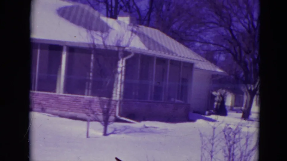 The final frame holds on the screened porch and snowy front yard of the Orlando house, with bare trees and film scratches visible.