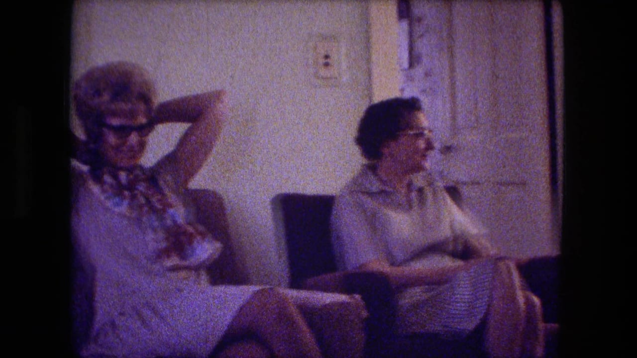 Fort Wayne 1974 home-movie frame showing two women seated in a living room, with one leaning back and adjusting her hair.