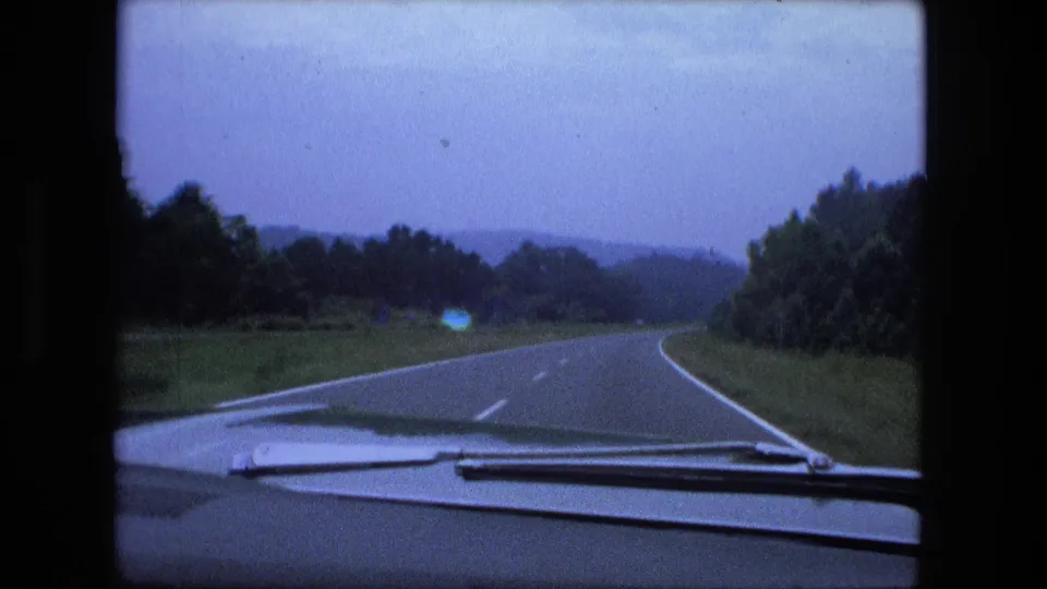 1974 home-movie frame from inside a car, looking down a quiet curving rural road in the Fort Wayne trip footage.