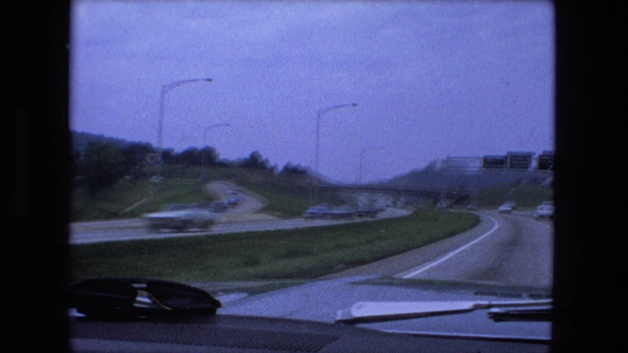 Curving highway ramp seen over a car dashboard with traffic ahead.