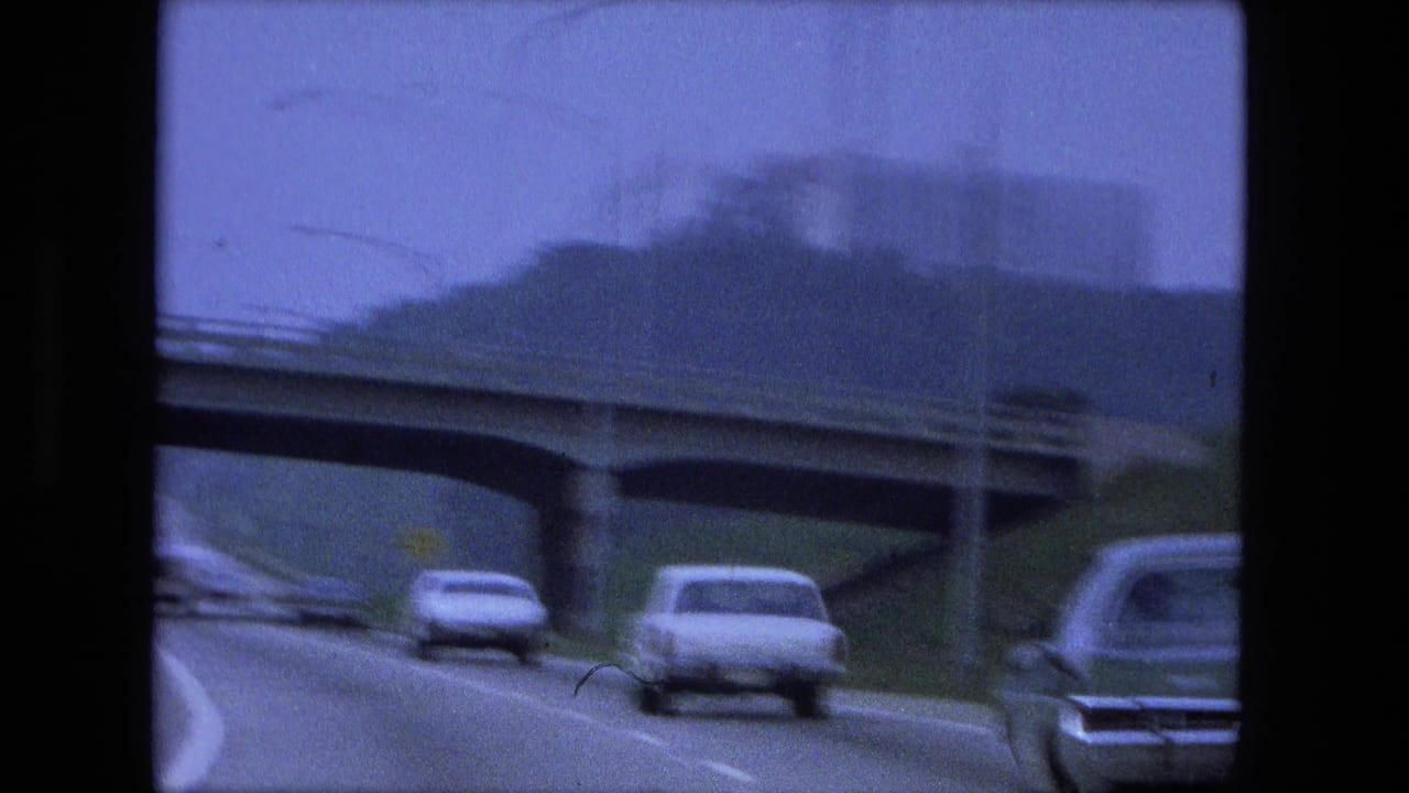 Blurred cars pass under an overpass on a divided highway.