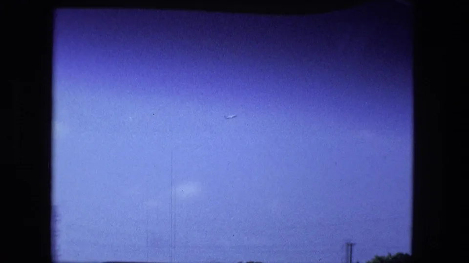 Fort Wayne 1974 home-movie frame tilted upward during the drive, showing blue sky, bridge rail, and a narrow strip of treetops.