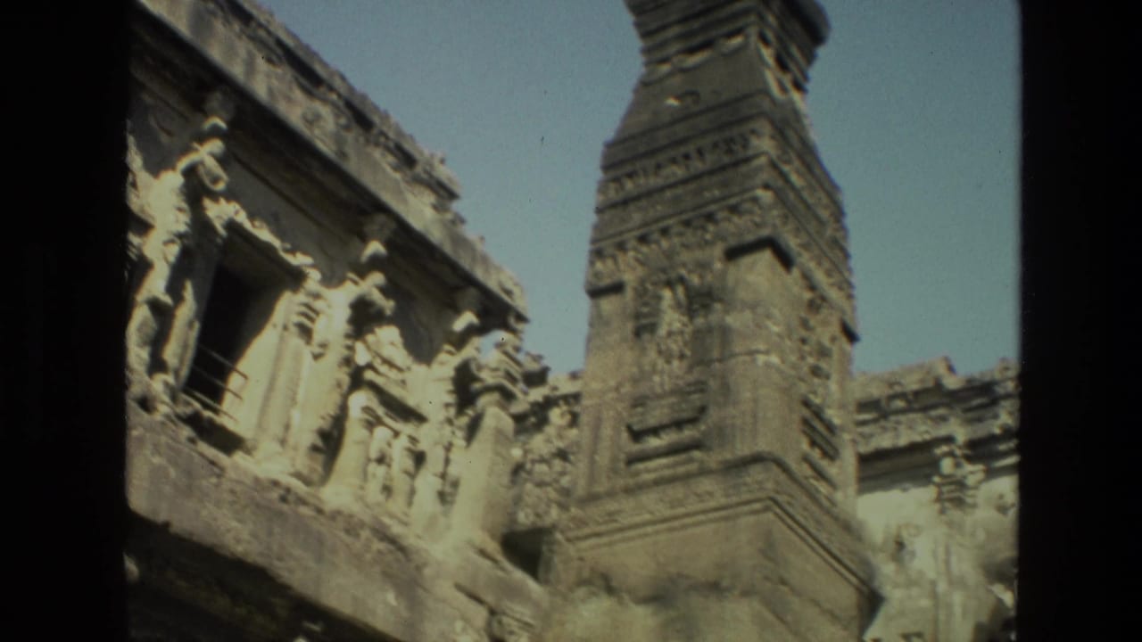 1974 India 8mm frame showing a sunlit carved stone temple facade with a tall spire and dark vertical film-frame edge.
