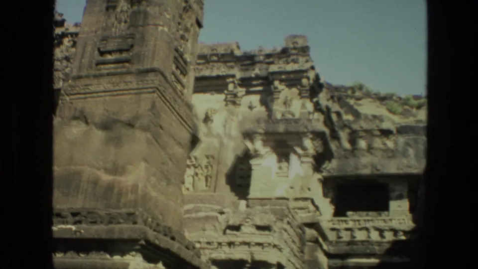1974 India 8mm frame showing a weathered temple structure with carved panels, a spire base, and a dark rectangular opening.
