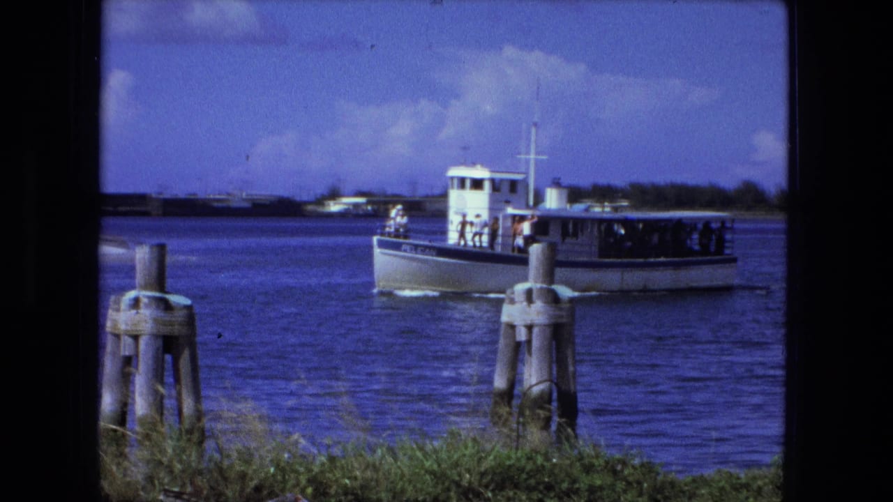 Small passenger boat farther right on the river with pilings in front.