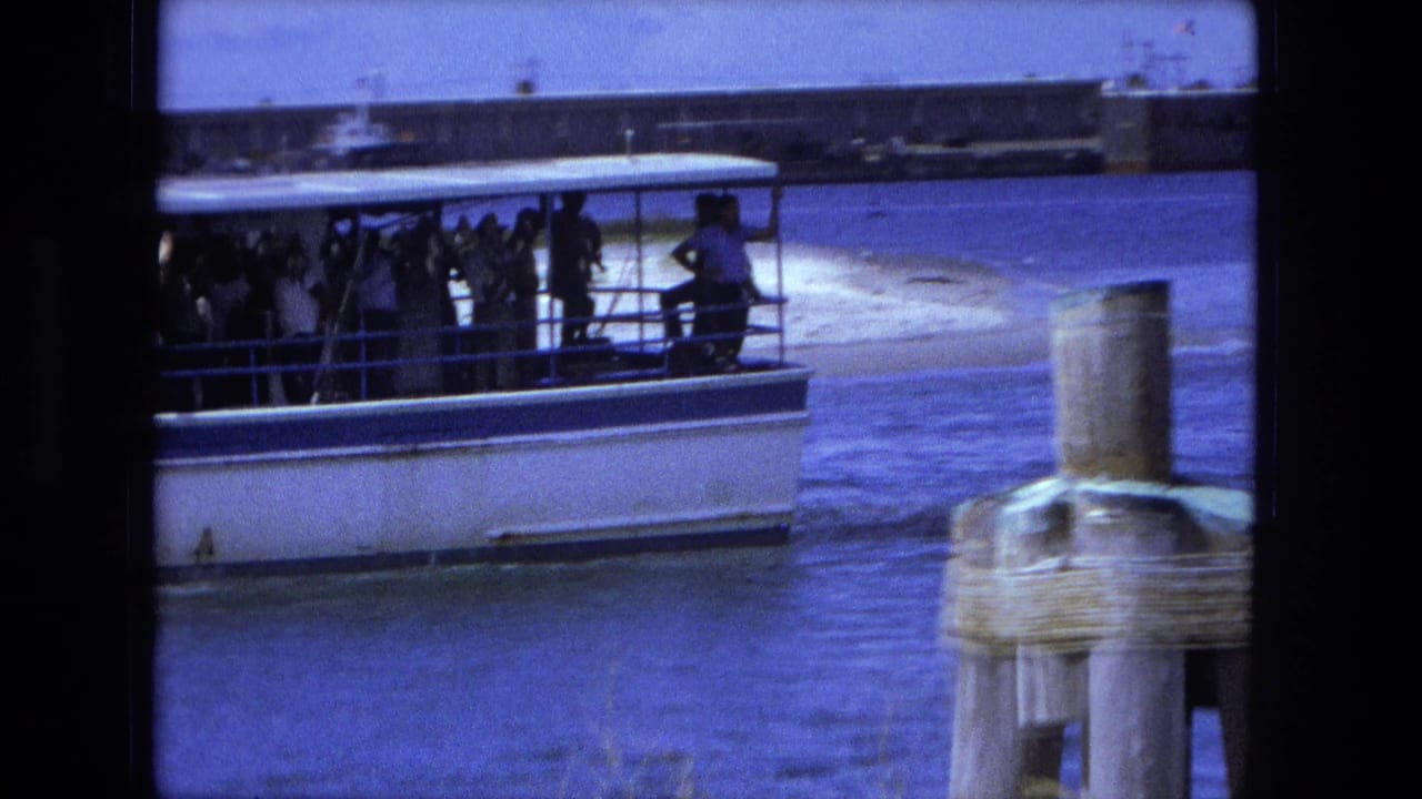 Passenger ferry moves across water near a foreground piling.