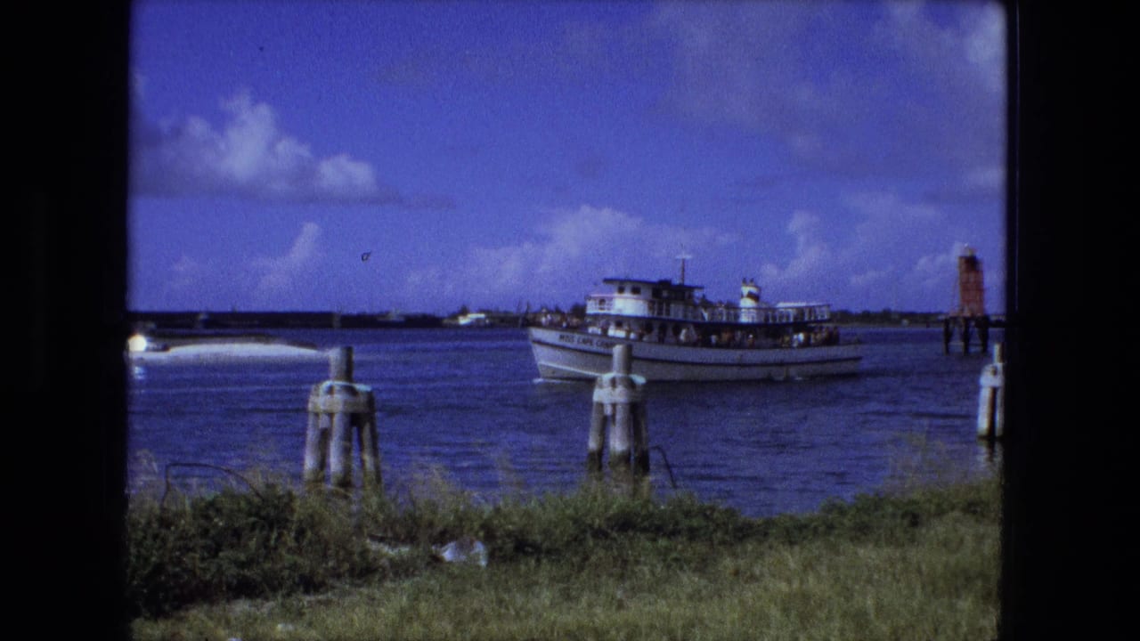 The white passenger boat continues across the water in this 1974 home-movie frame, with passengers visible as small figures on deck.